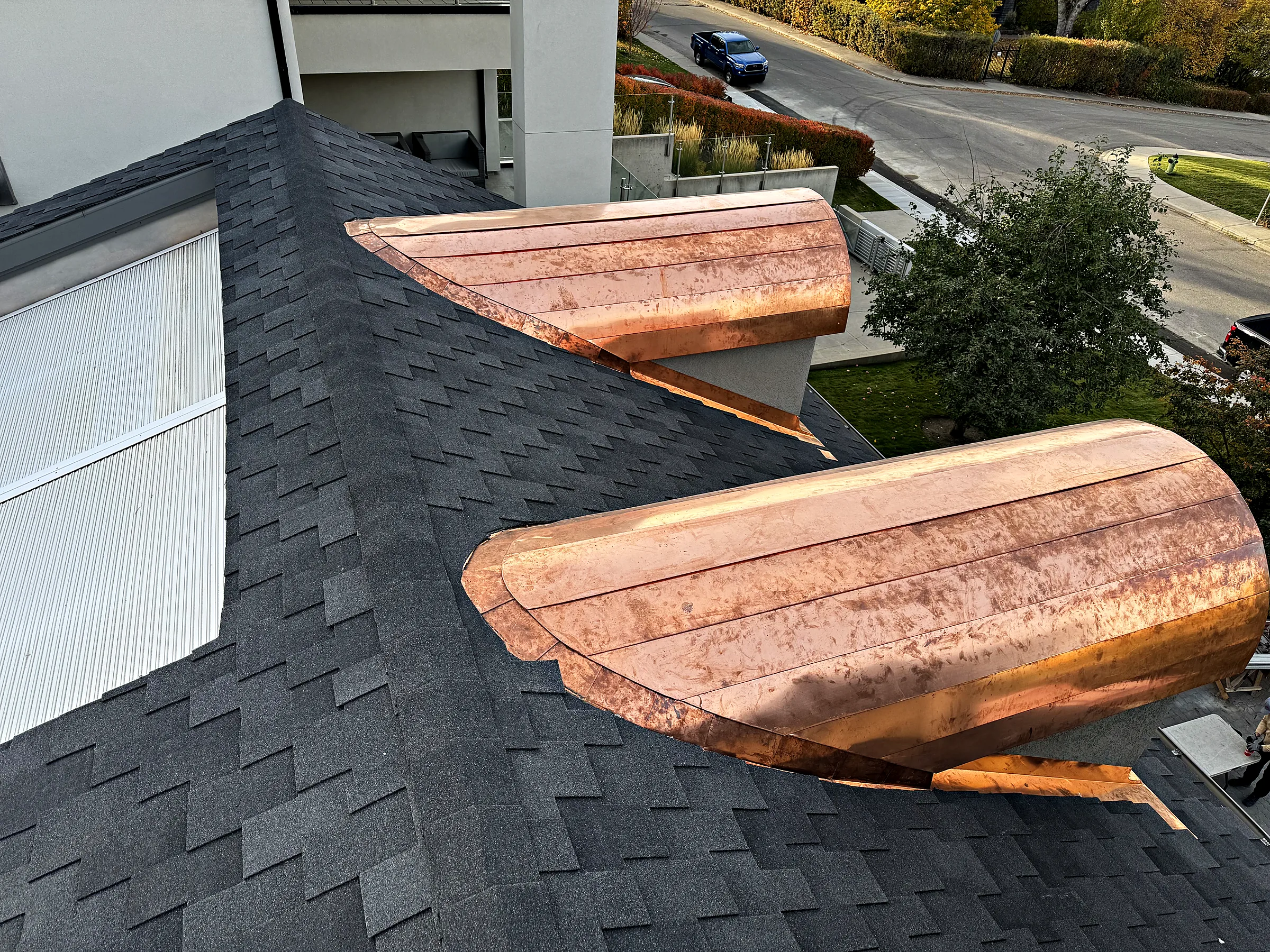 Two new copper bay roofs on a shingled house