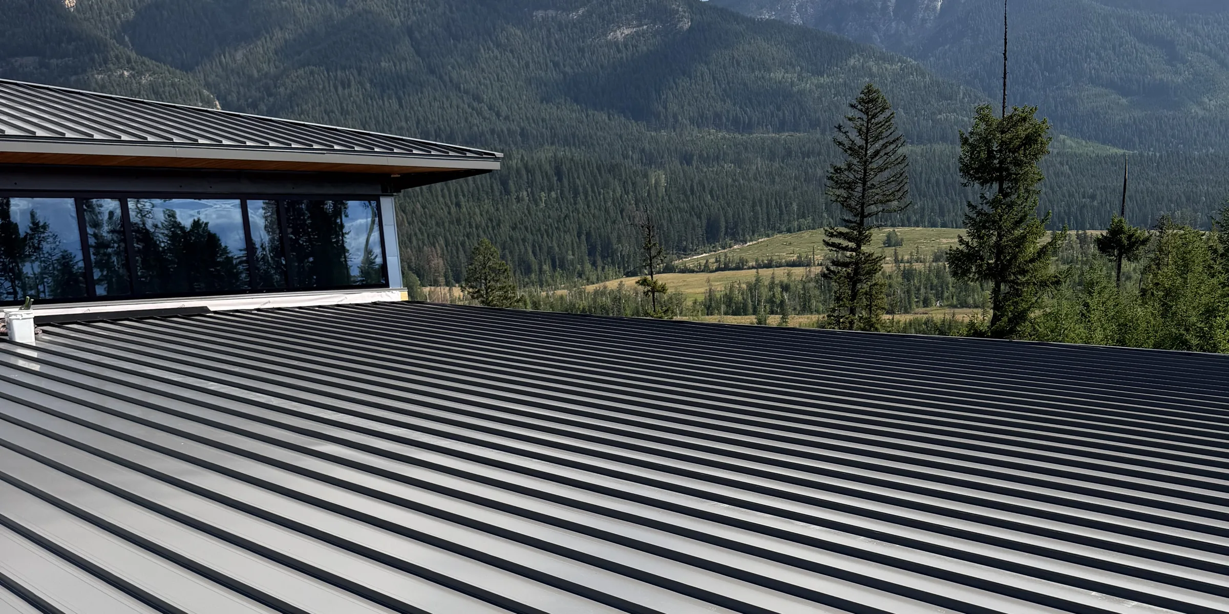 Low-slope double-lock standing seam roof in Golden, BC, with mountains behind