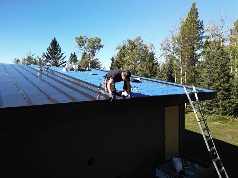 Crew seaming a standing seam roof in Mountain View County